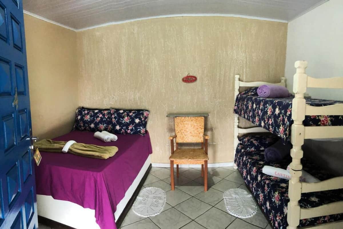 A small, compact room with a single bed, a chair, and a bunk bed.