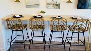 Una cucina moderna con isola centrale, quattro sedie in vimini e lampade a sospensione fissate alla parete.