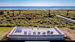 Una località balneare con terrazza, lettini e vista sull'oceano.