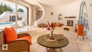 Una sala moderna con una mesa redonda, muebles de mimbre y vistas a una piscina y zona exterior.