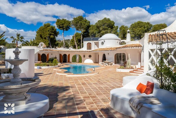 A pool area with a fountain, white outdoor furniture, and a tiled patio. - Villa MINARET by Abahana Villas (Benissa)