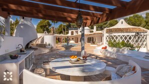 Un patio al aire libre con una mesa redonda, asientos, una fuente y una pérgola.