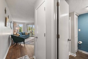 A hallway leading to a living room with a blue sofa, a lamp, and a view of the outdoors. - Golf Views - Outdoor pool, 3 Beds, 1 mile 2 Beach (North Myrtle Beach)