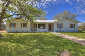 A single-story house with a front porch, a small front yard, and a clear blue sky. - River Oaks Ranch-30 Acres-5 Min to Main Street! (Fredericksburg)