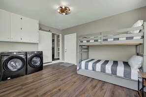 A compact room with a bunk bed, a washing machine, and a door leading to another room. - River Oaks Ranch-30 Acres-5 Min to Main Street! (Fredericksburg)