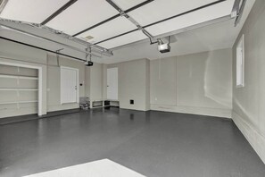 Um quarto amplo, bem iluminado, com teto alto, janelas grandes e piso de concreto.
