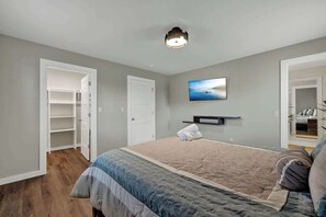 Quarto com cama, armário, porta, prateleira na parede e uma pintura.