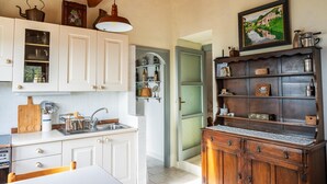 Een keuken met witte kastjes, een houten aanrechtblad en een hanglamp.