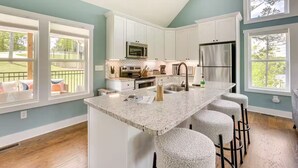 A modern kitchen with white cabinets, a granite countertop, and a stainless steel refrigerator. - Lakefront Luxury Retreat, Kayaks, Game Room, Firepit, Pool Table & Private Dock (Wedowee)