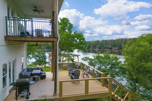 A two-story building with a balcony overlooking a lake, outdoor seating, and a pergola. - Lakefront Luxury Retreat, Kayaks, Game Room, Firepit, Pool Table & Private Dock (Wedowee)