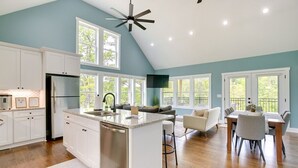 A spacious kitchen with a central island, white cabinetry, and a dining area with a table and chairs. - Lakefront Luxury Retreat, Kayaks, Game Room, Firepit, Pool Table & Private Dock (Wedowee)