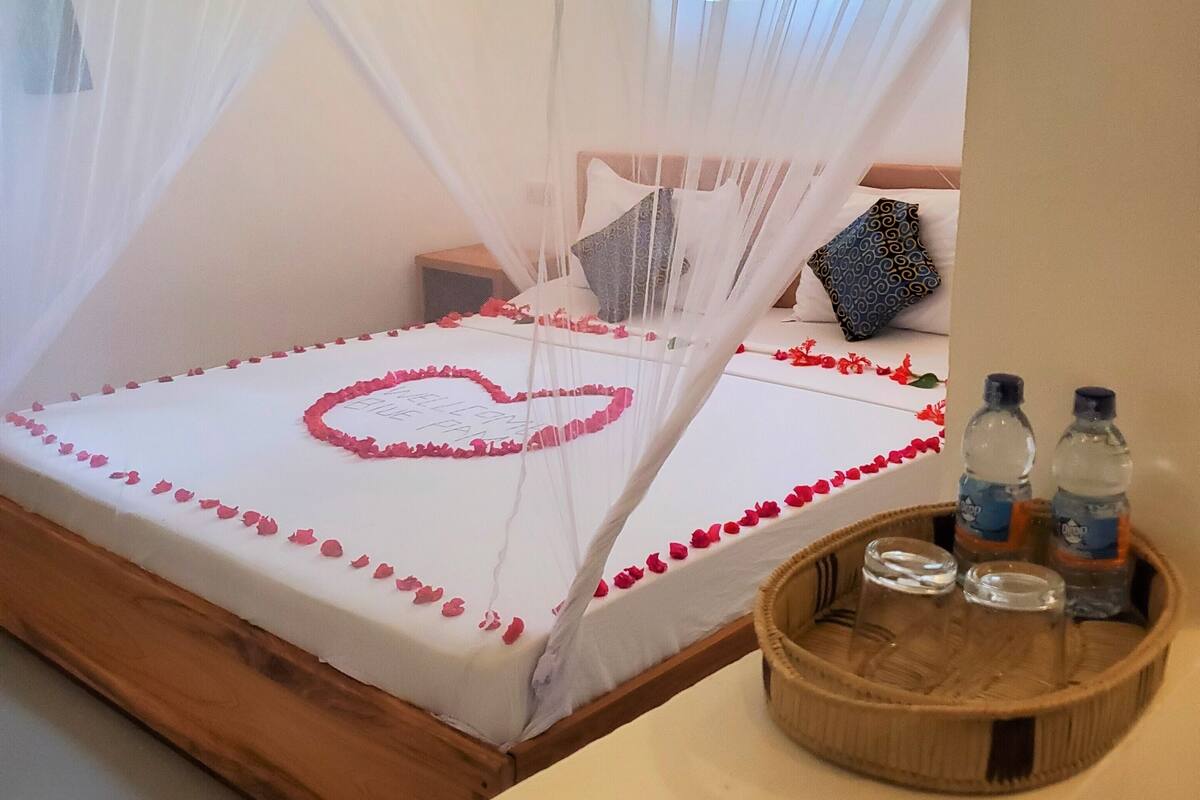 A bed with a canopy, a heart-shaped decoration, and a tray with bottles.