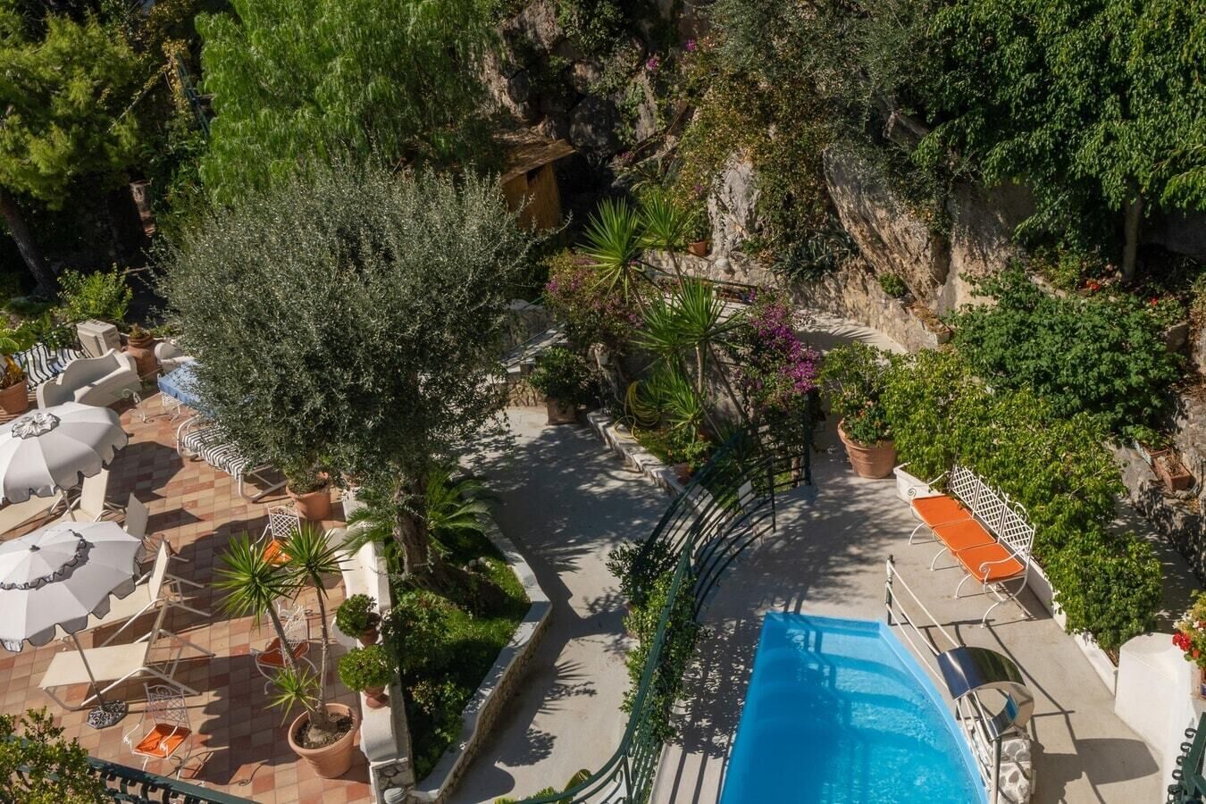 A poolside area with lounge chairs, umbrellas, and potted plants.