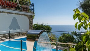 A pool with a water slide, surrounded by a stone wall and a balcony with a railing. - Villas Gru di Mare, Positano (Positano)