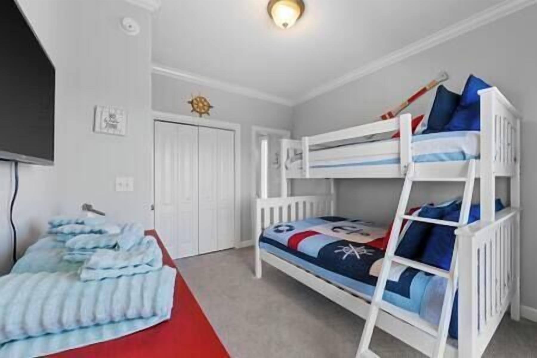 A bunk bed room with a red carpet, white walls, and a ceiling light.