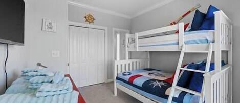 A bunk bed room with a red carpet, white walls, and a ceiling light.