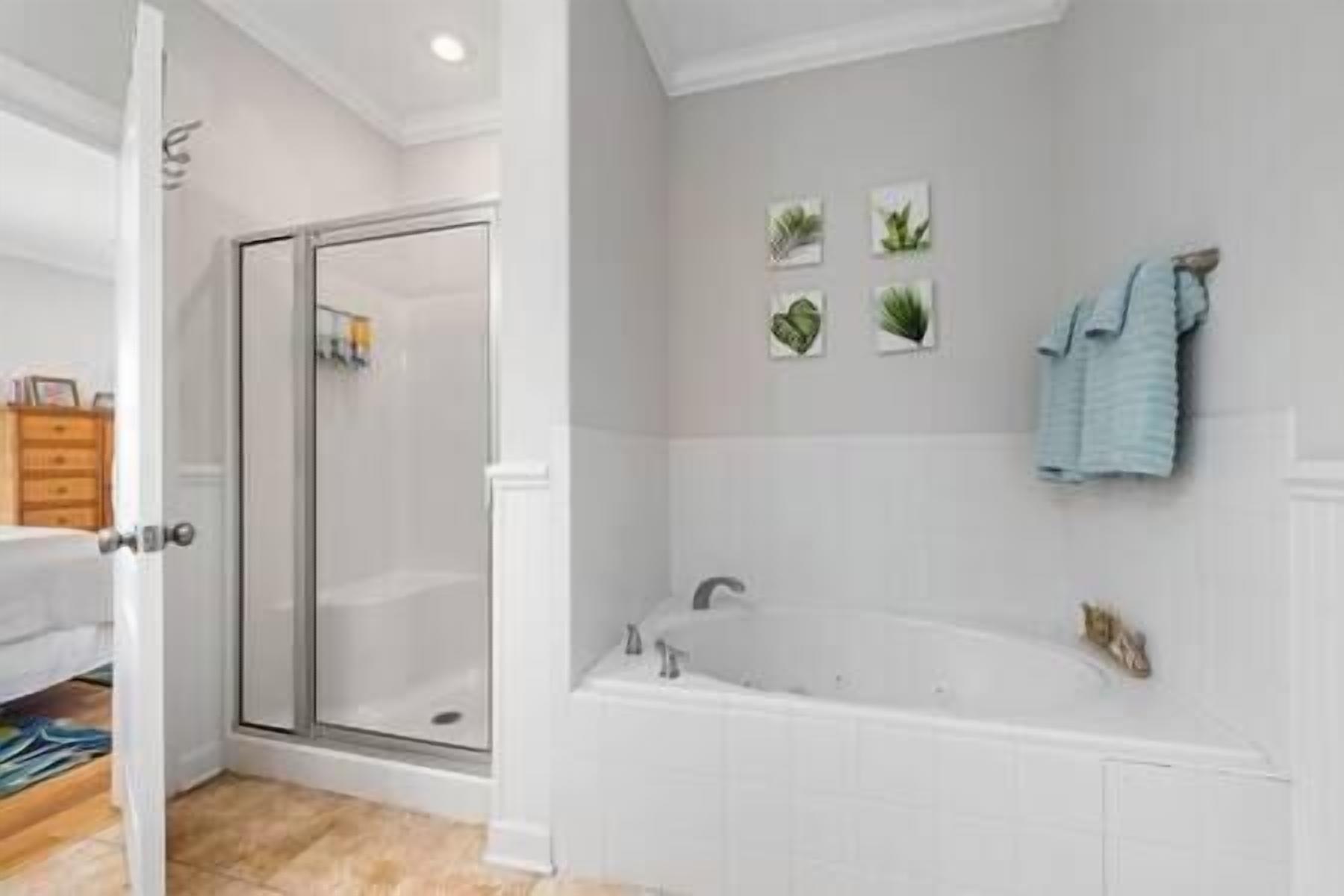 Un baño con cabina de ducha de vidrio, una bañera y un perchero con toalla.