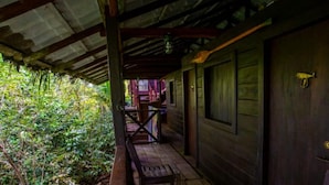 A wooden cabin with a porch, a bench, and a door. - Morro Terco Hotel (Nuquí)