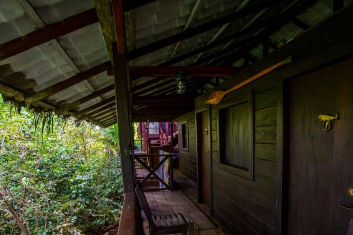 Une cabane en bois avec une véranda, un banc et une porte.