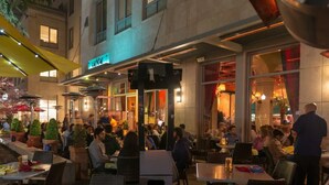 An outdoor dining area with tables and chairs, a neon sign, and a building facade in the background. - Large 2BD, 2BA Private Whole House Walking Distance from Downtown Mountain View! (Mountain View)