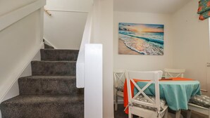 A staircase leading to a dining area with a painting of a beach scene.
