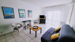Un soggiorno con un divano, due poltrone, un tavolino e una televisione. Tre quadri appesi alla parete.