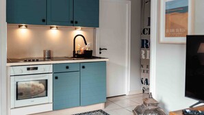 A compact kitchen with teal cabinets, a white stove, and a black faucet. - Cozy apartment by the sea (La Teste-de-Buch)