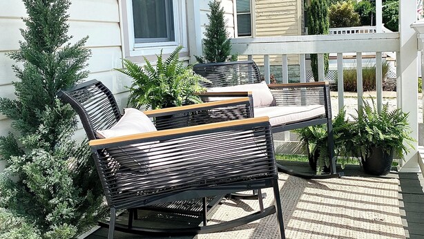 A covered porch with a wicker sofa and potted plants. - Lakefront on Main  (Elmer)