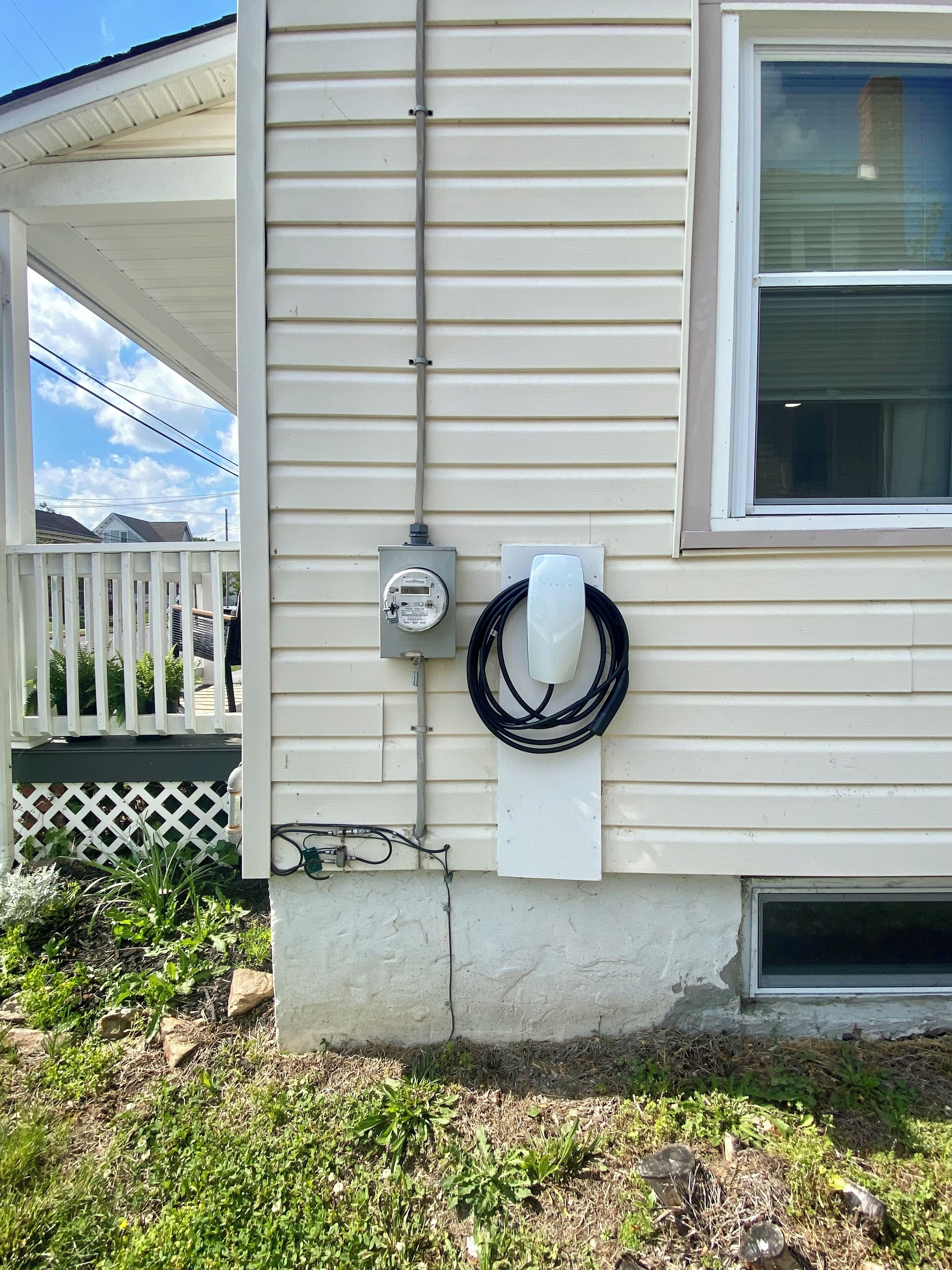 A utility meter and a white electrical box mounted on a house exterior wall.