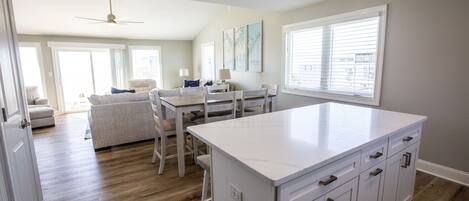 A spacious kitchen with a large island, wooden flooring, and a dining area with a table and chairs.
