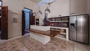 Una cocina moderna con una isla central, electrodomésticos de acero inoxidable, luces colgantes y baldosas de suelo estampadas.