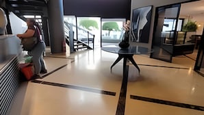 Um hall amplo com teto alto, uma mesa central e uma escadaria que dá acesso aos andares superiores.