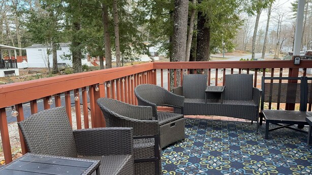 Eine Terrasse mit Korbmöbeln und einem gemusterten Teppich.