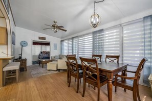 Un comedor con mesa y sillas de madera, ventilador de techo y candelabro.