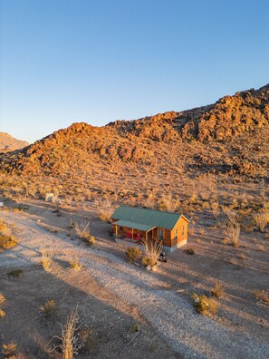 A small cabin with a green roof in a desert landscape. - Cabin 2 at Widows Peak • Terlingua, Big Bend (Terlingua)