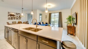 Una cucina moderna con un'isola grande, elettrodomestici in acciaio inossidabile e luci a sospensione.