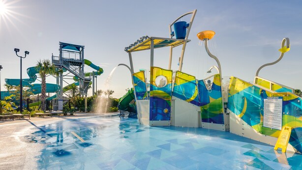 Un parco acquatico con piscina, scivoli e area giochi d'acqua.