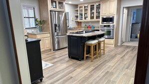 Una cucina moderna con mobili in legno, elettrodomestici in acciaio inossidabile e un'isola centrale con sgabelli.