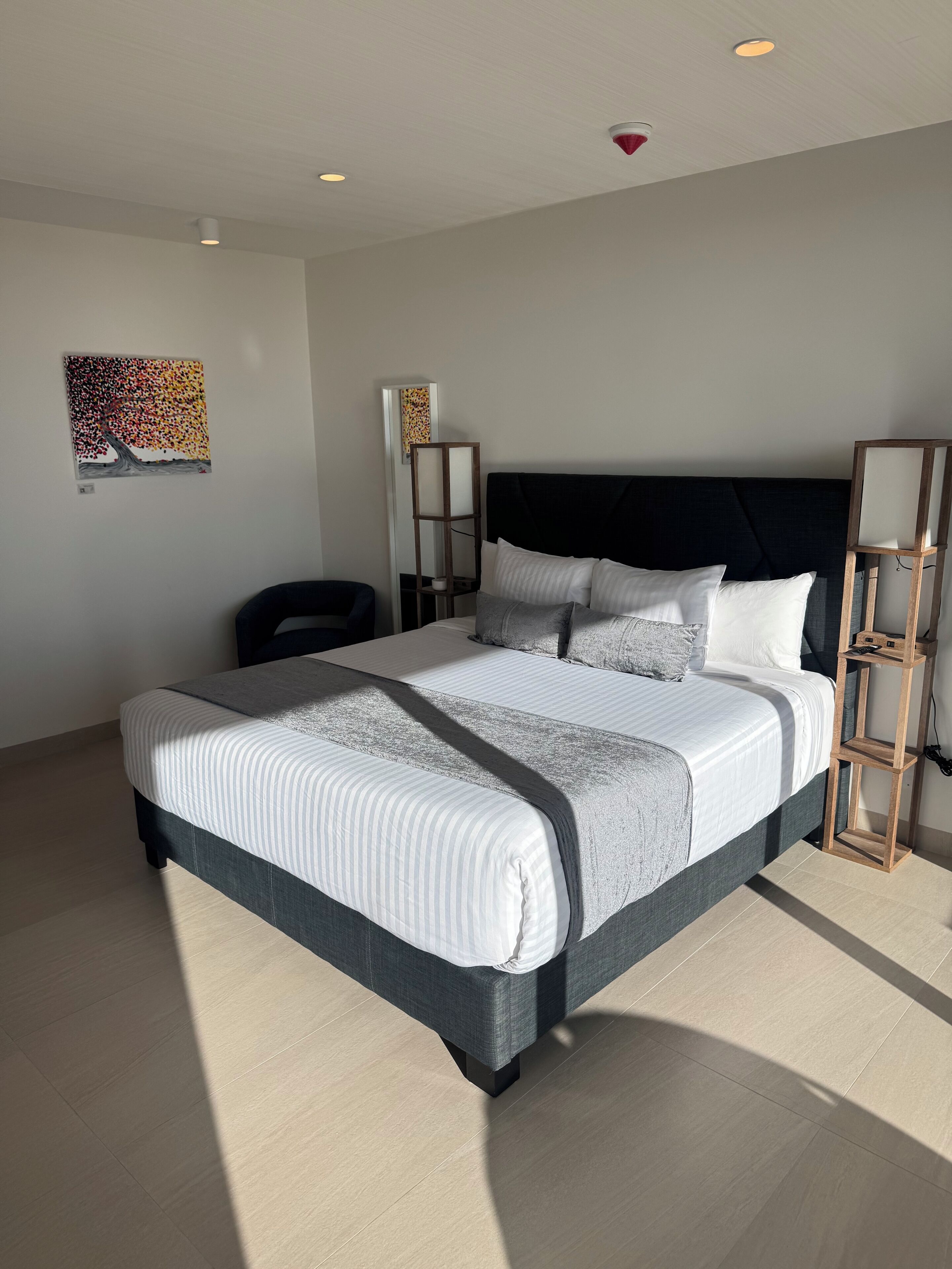Ein modernes Schlafzimmer mit einem großen Bett, einem dunklen Kopfteil und einem Holznachttisch.
