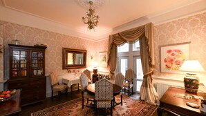 A formal dining room with a chandelier, a large mirror, a table with chairs, and a patterned rug. - The Townhouse (Ayr)