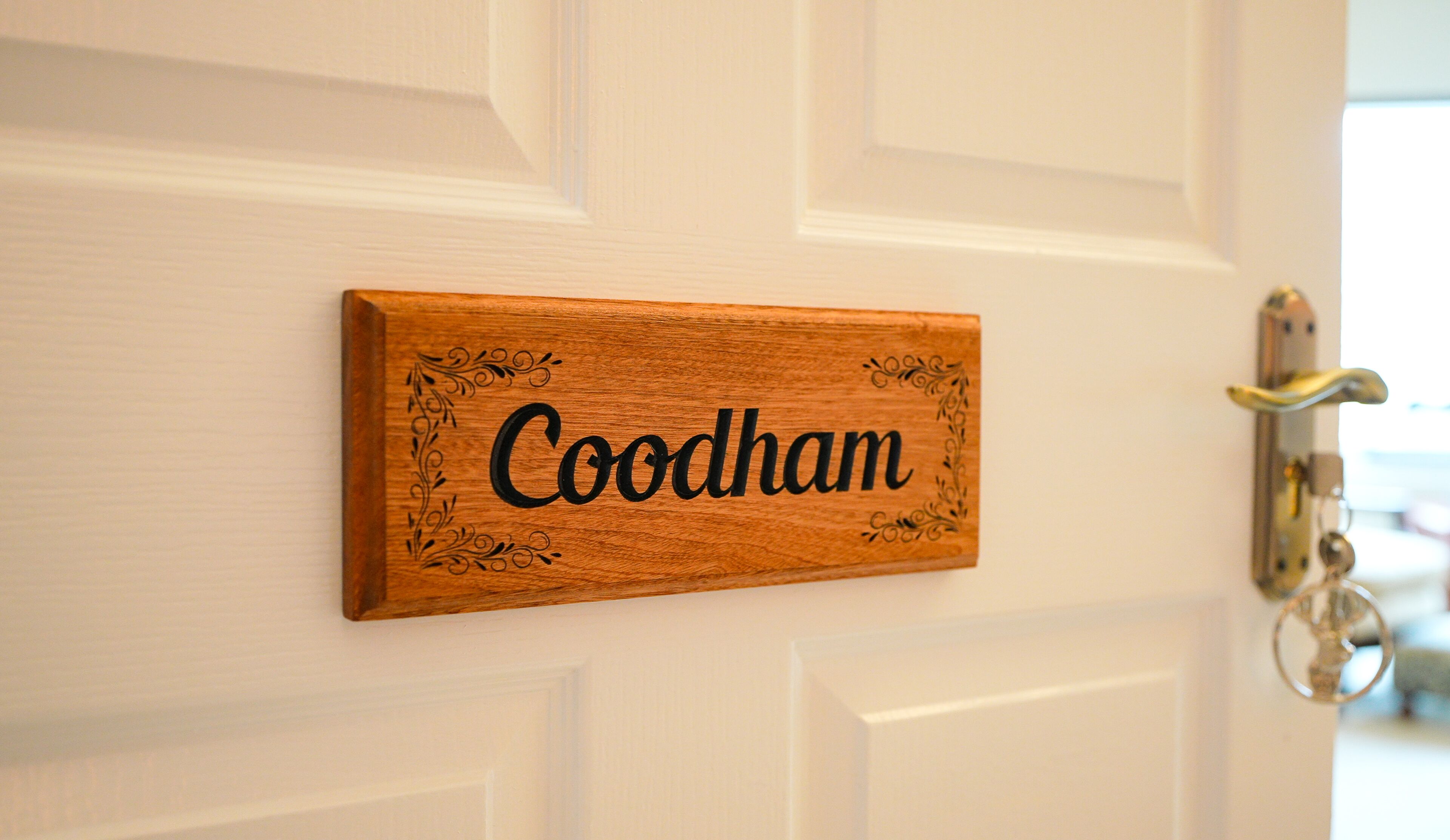A wooden nameplate with the name "Goodham" mounted on a white door.
