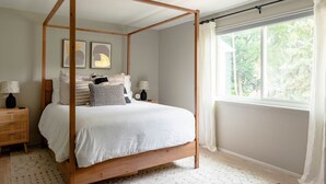A four-poster bed in a bedroom with a window, a bedside table, and a nightstand.