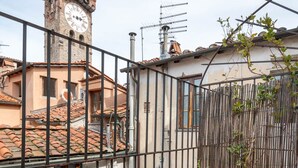 A balcony with a round table, a potted fern, and a bowl of strawberries. - Panoramic Penthouse with Terrace, 2 bedrooms 2 bathrooms inside the Walls of Lucca (Lucca)