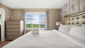 Ein Hotelzimmer mit einem großen Bett, einem Schminktisch und einem Fenster mit Blick auf die Landschaft.