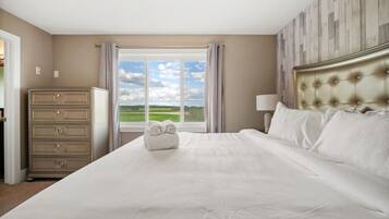 Ein Hotelzimmer mit einem großen Bett, einem Schminktisch und einem Fenster mit Blick auf die Landschaft.
