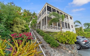 A multi-story building with balconies, surrounded by lush greenery and a stone pathway. - Ocean Views · Walk to Cruz Bay · Beach Ready (Cruz Bay)