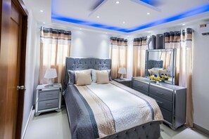 A modern bedroom with a large bed, bedside tables, a dresser, and a mirror. - Amplio y Hermoso Apartamento (Santiago de los Caballeros)