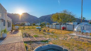 Un jardin avec un jacuzzi, des meubles de patio et une vue sur les montagnes en arrière-plan.