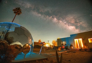 A starry night sky with a telescope and a geodesic dome structure.