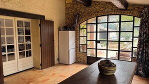 Una cocina rústica con pared de piedra, una mesa de madera y un ventanal con vistas al exterior.